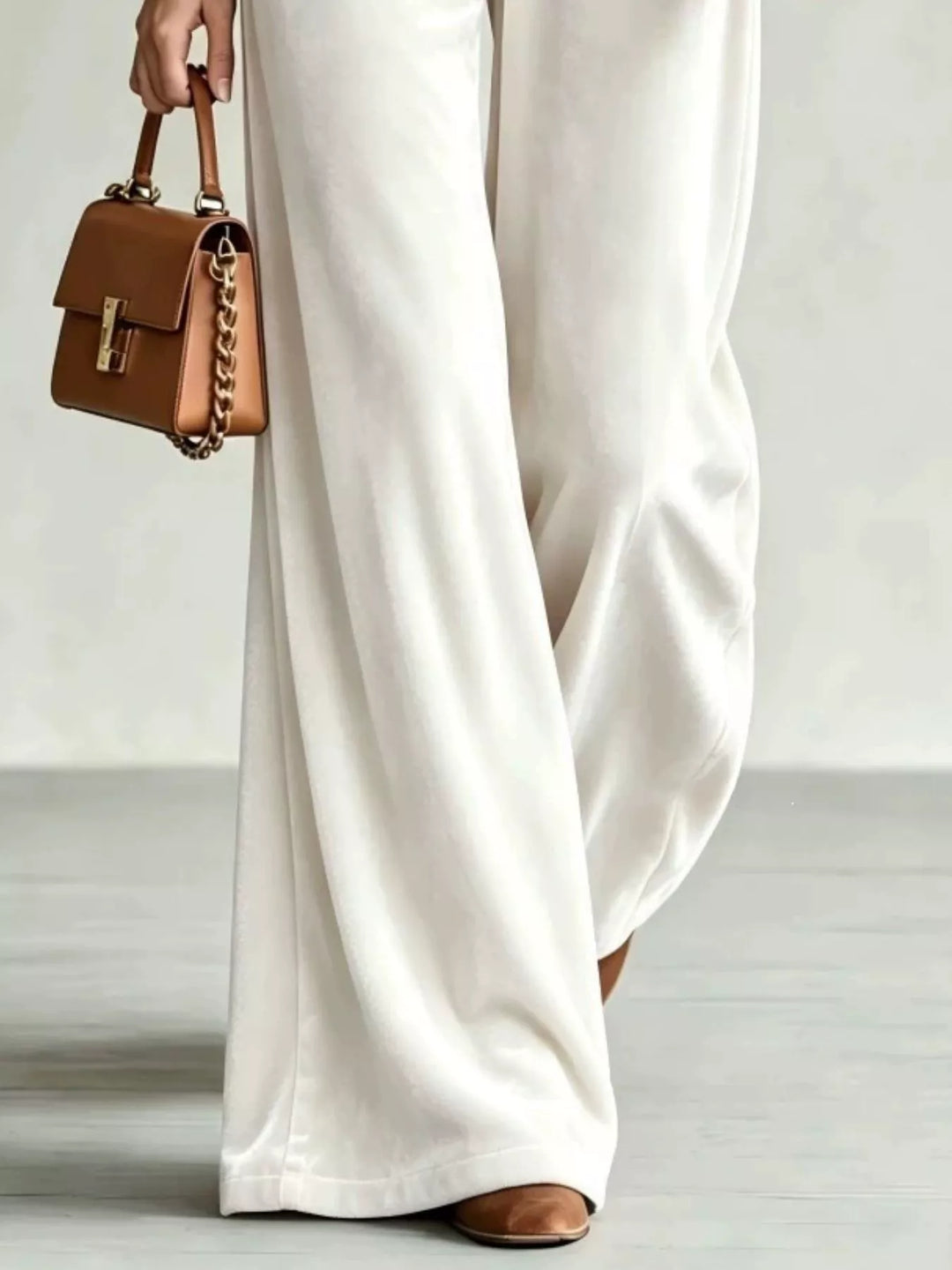 Lower view of the ivory soft pile wide leg pants and leather handbag