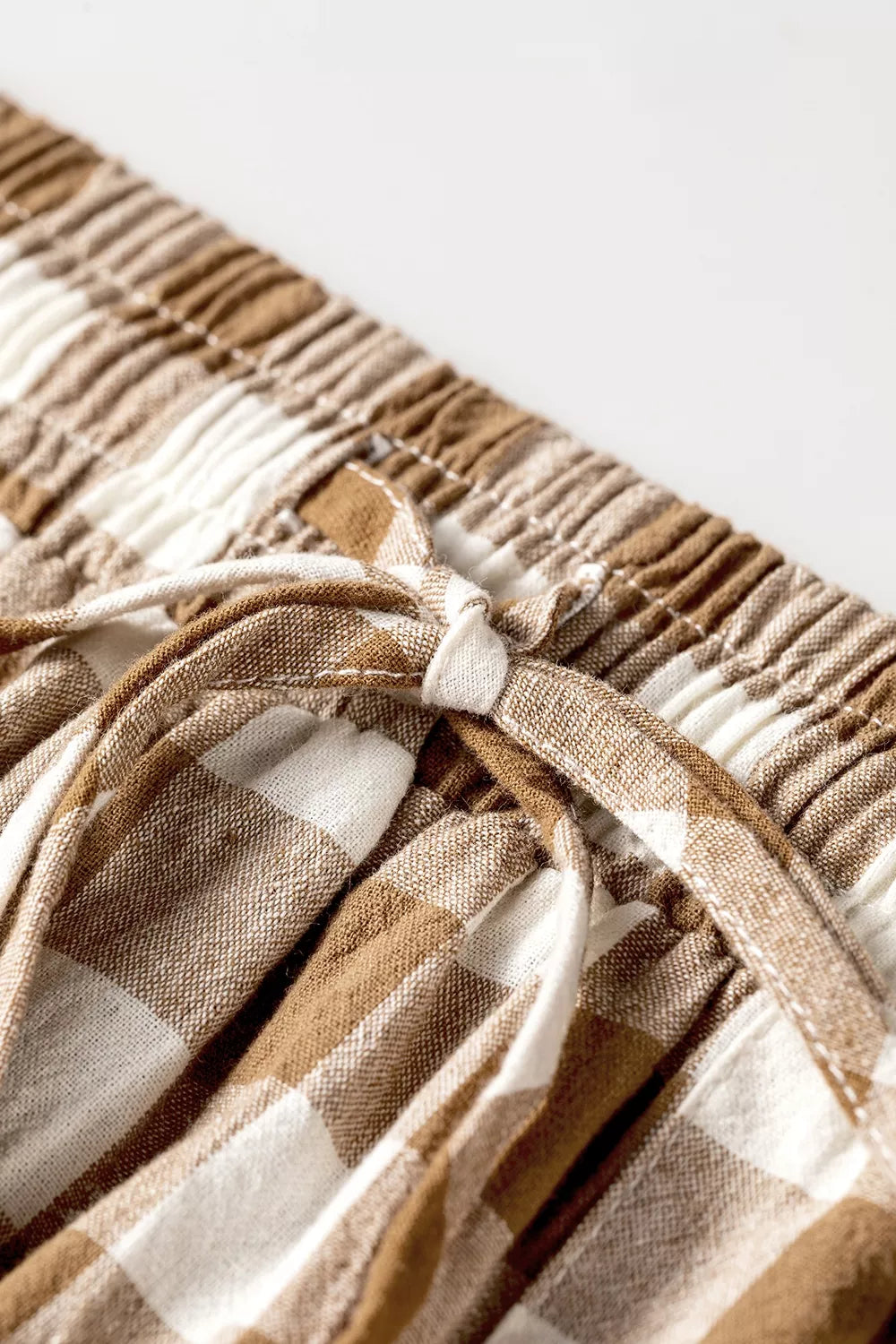 Close-up of the tied drawstring on the brown gingham waistband