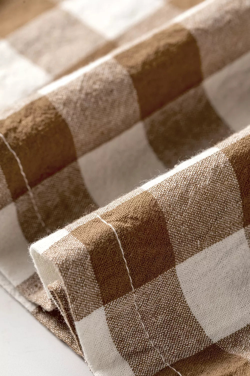 Close-up of the brown gingham pants hem and stitching