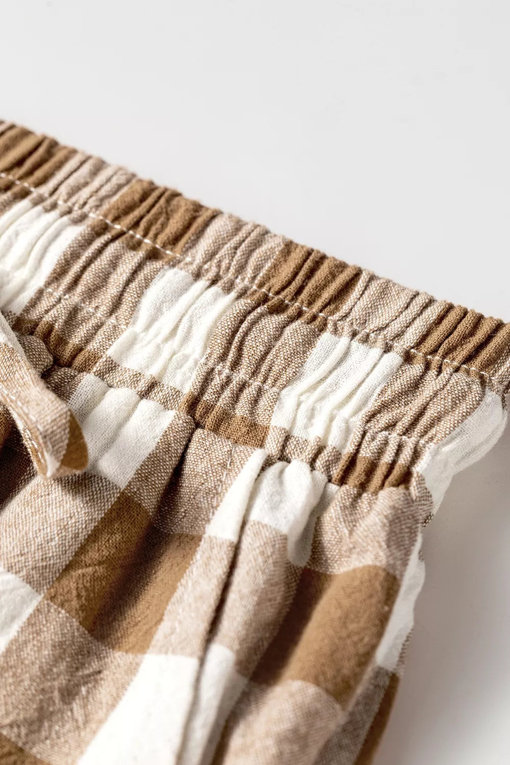 Detail of the brown plaid elastic waistband and drawstring, laid flat