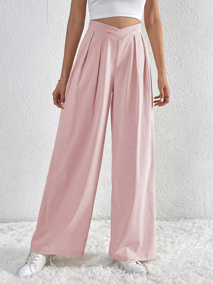 Light pink pleated wide leg pants with high waist, front view with sneakers