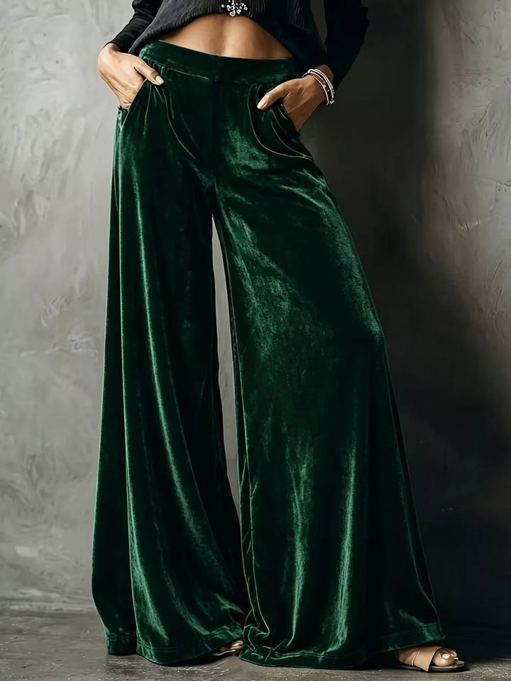 Emerald green high waisted wide leg pants with a glossy velvet-look sheen