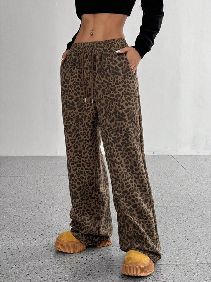 Chocolate leopard print wide leg pants with hands in pockets, front view