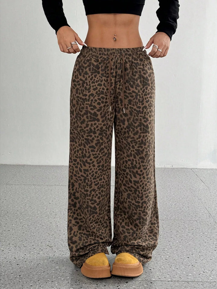Chocolate leopard print elastic waist pants, full length view with hands on hips