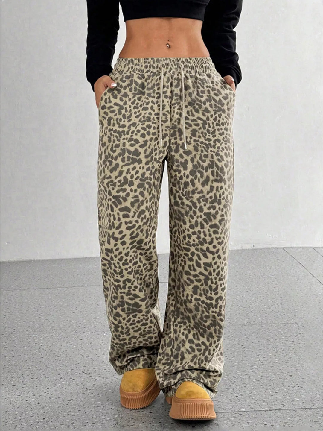 Khaki leopard print wide leg pants with elastic waist, hands in pockets
