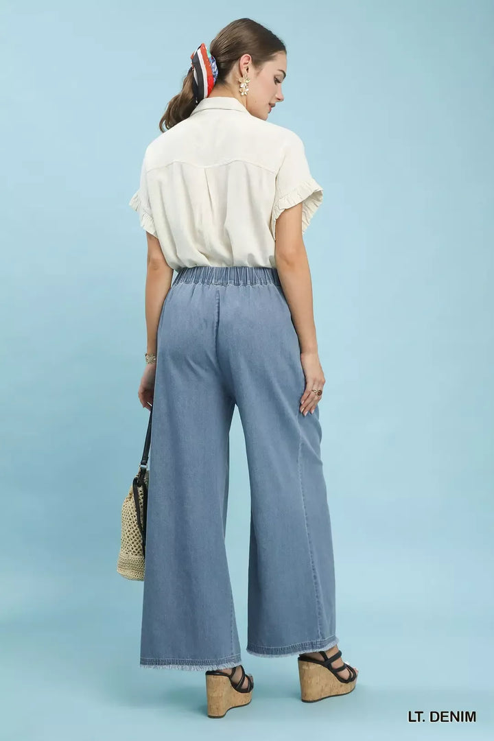 Back view of the light denim wide leg pants worn with a short sleeve blouse