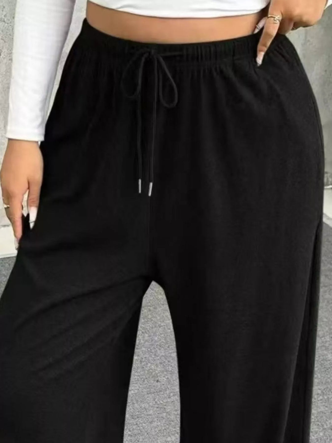 Close-up of the black ribbed pants waistband and drawstring tips