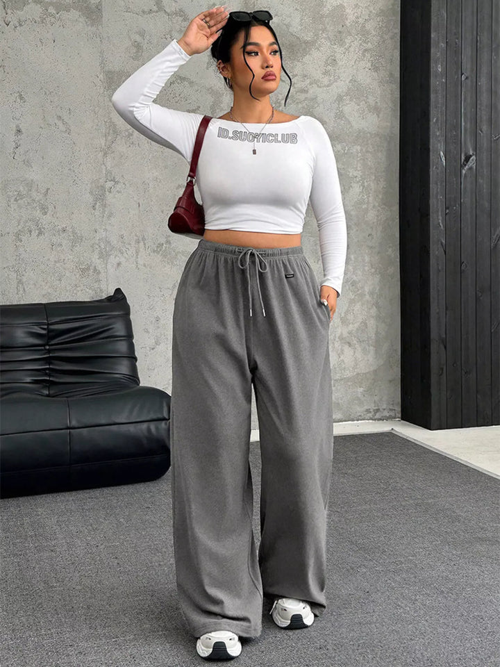 Gray wide leg pants styled with a white crop top and a red shoulder bag