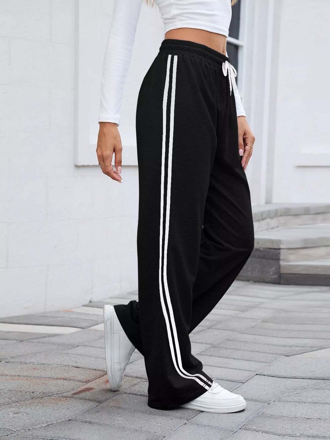 Black side striped wide leg pants, side view with white sneakers