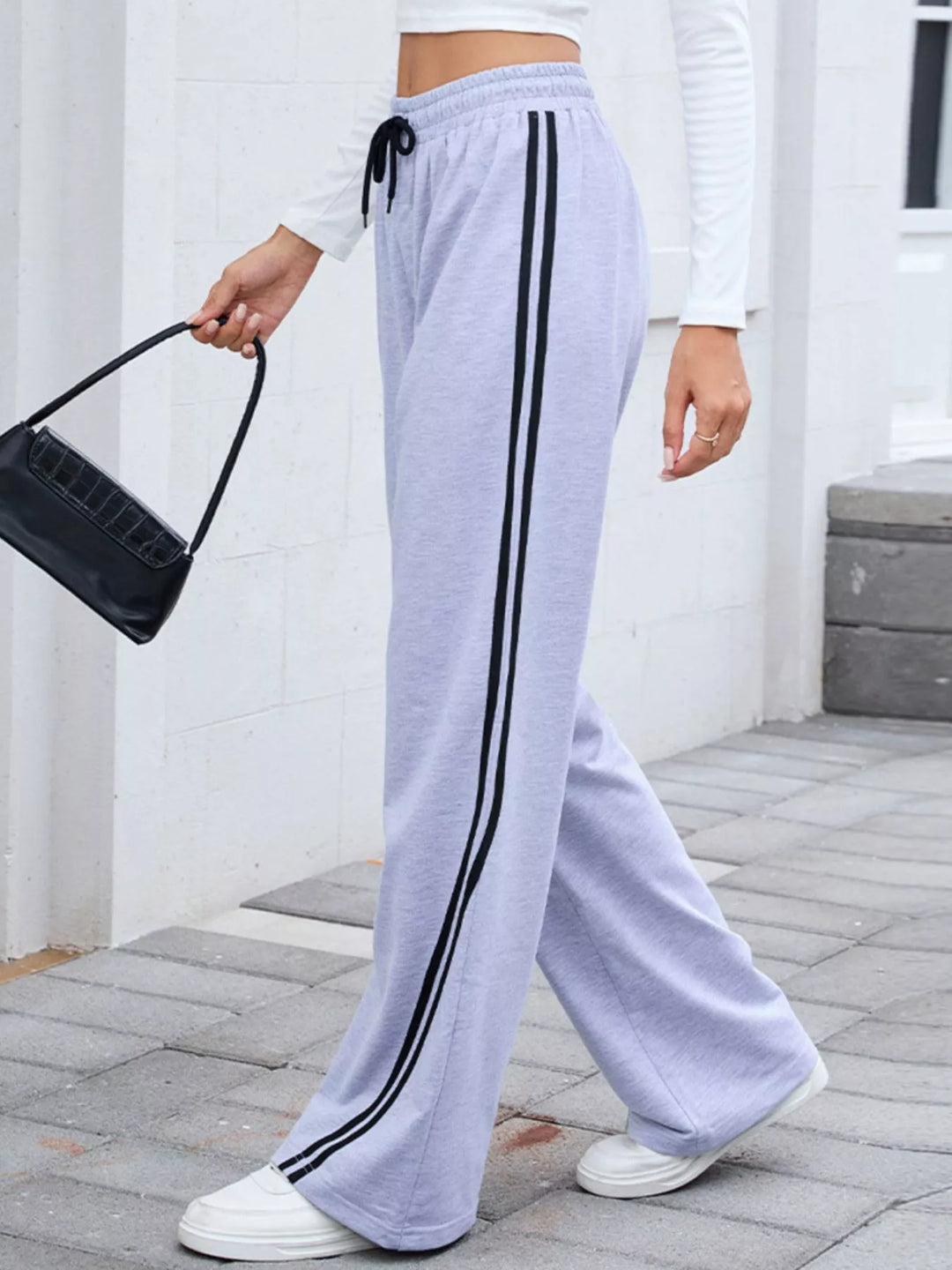Lavender striped wide leg pants carried with a black shoulder bag