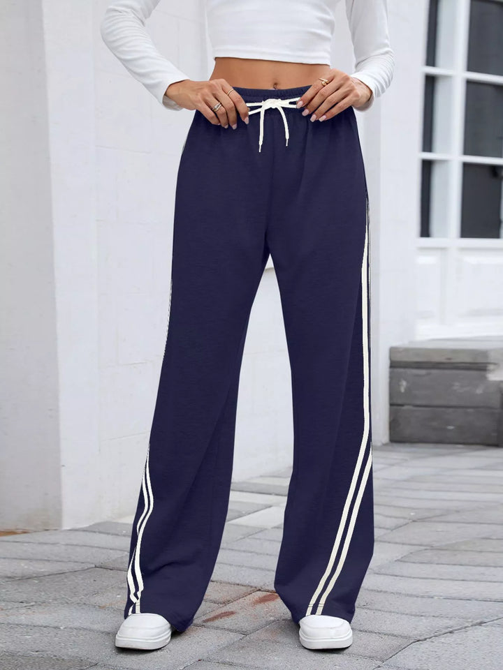 Navy side striped high rise pants, full length front view in sneakers