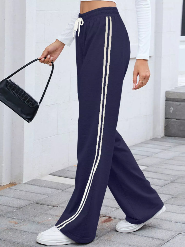 Navy striped wide leg pants walking with a black shoulder bag