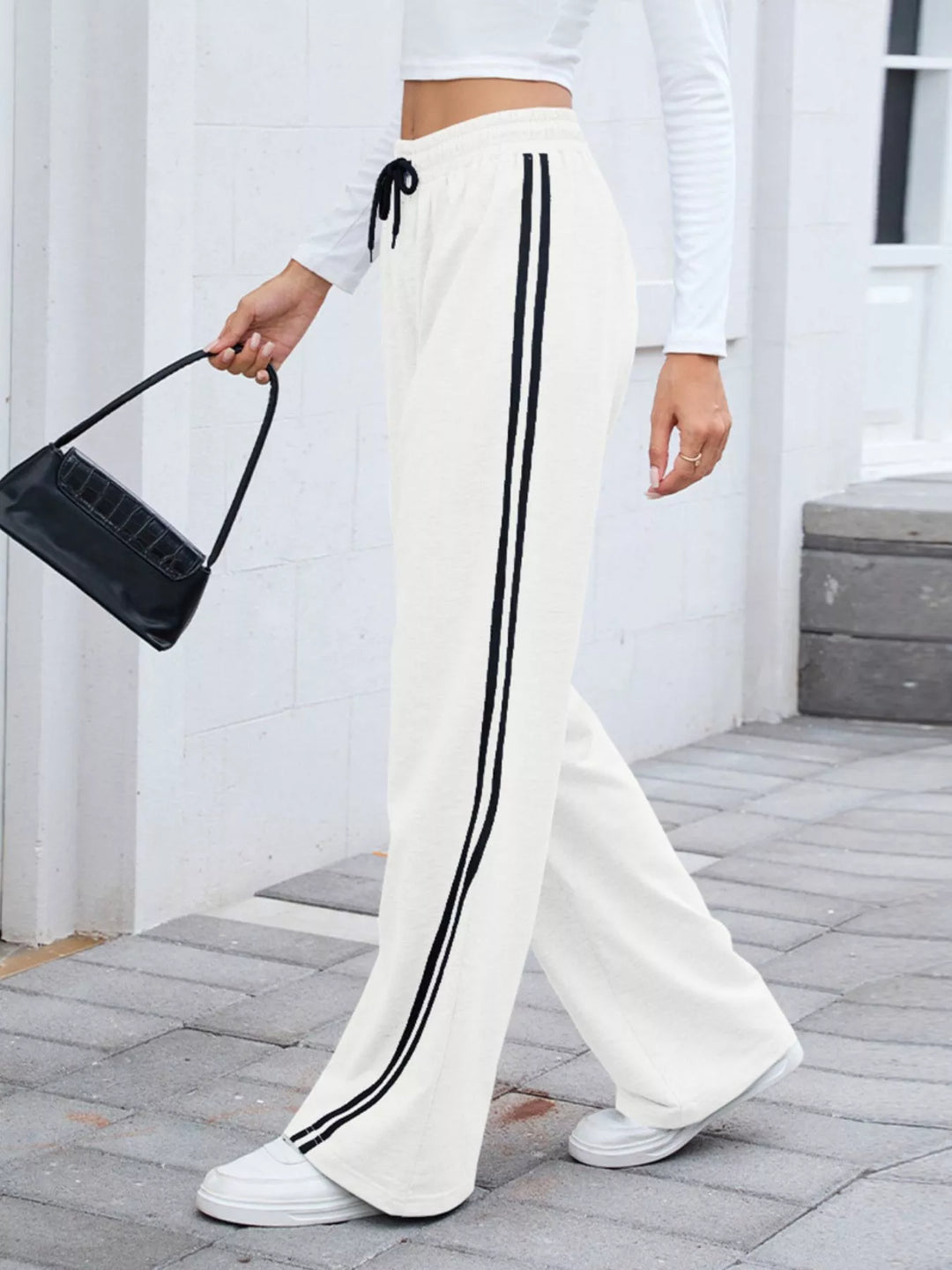 White side striped wide leg pants styled with a black shoulder bag