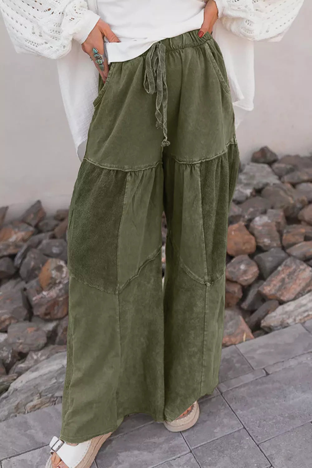 Olive green tiered pants worn with a white puff sleeve top outdoors