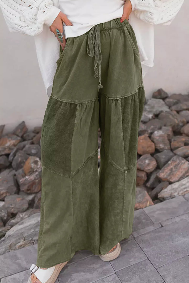 Olive green tiered pants worn with a white puff sleeve top outdoors