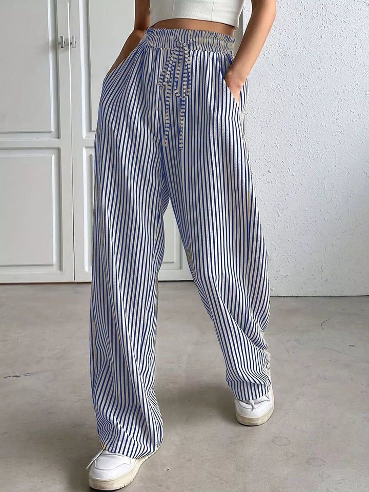 Blue striped wide leg pants with white sneakers, full length view