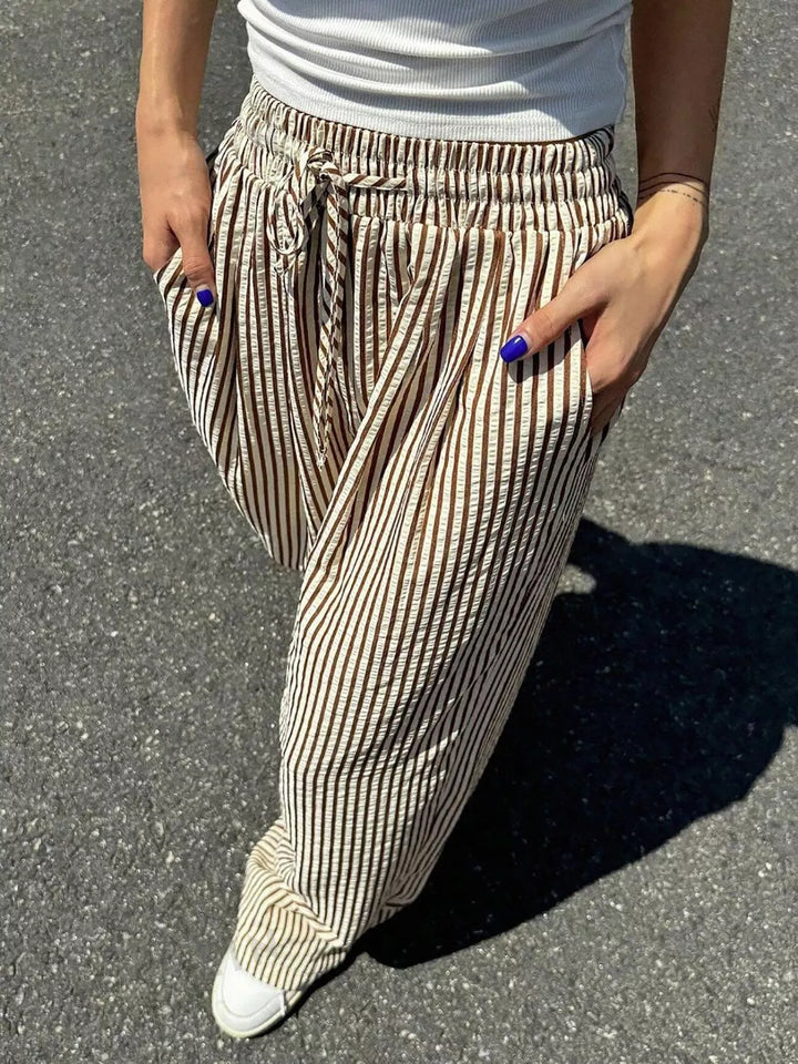 Close-up of the taupe pinstripe drawstring waist and hand in pocket