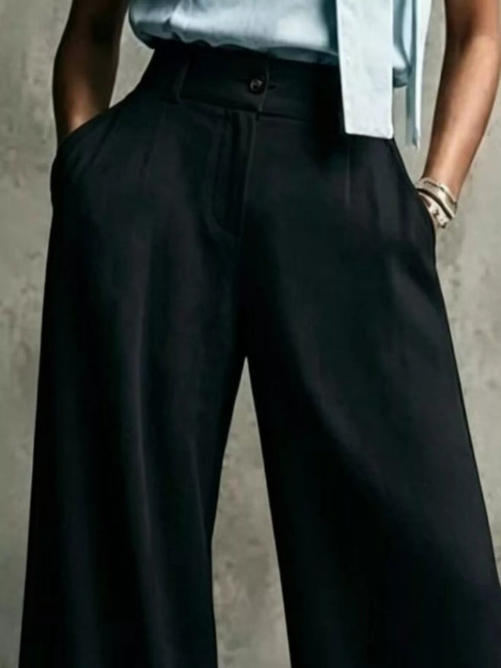 Black pleated button zip trousers, close-up at the waist