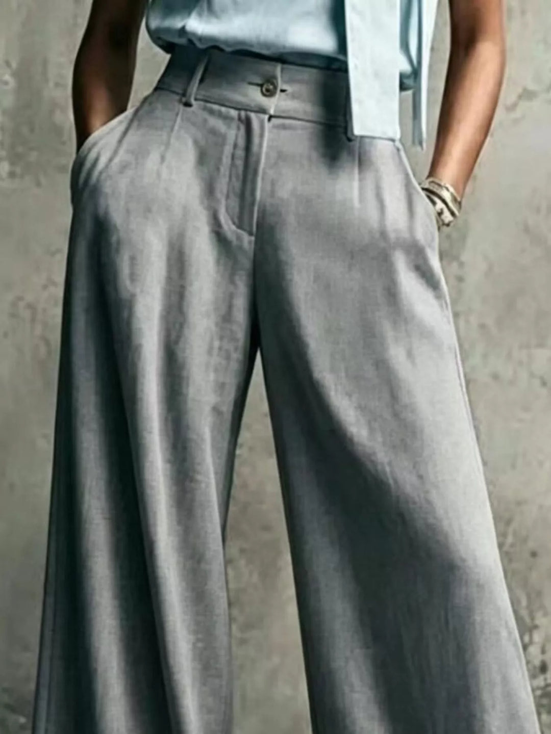 Gray pleated trousers, close-up of the waistband and button closure