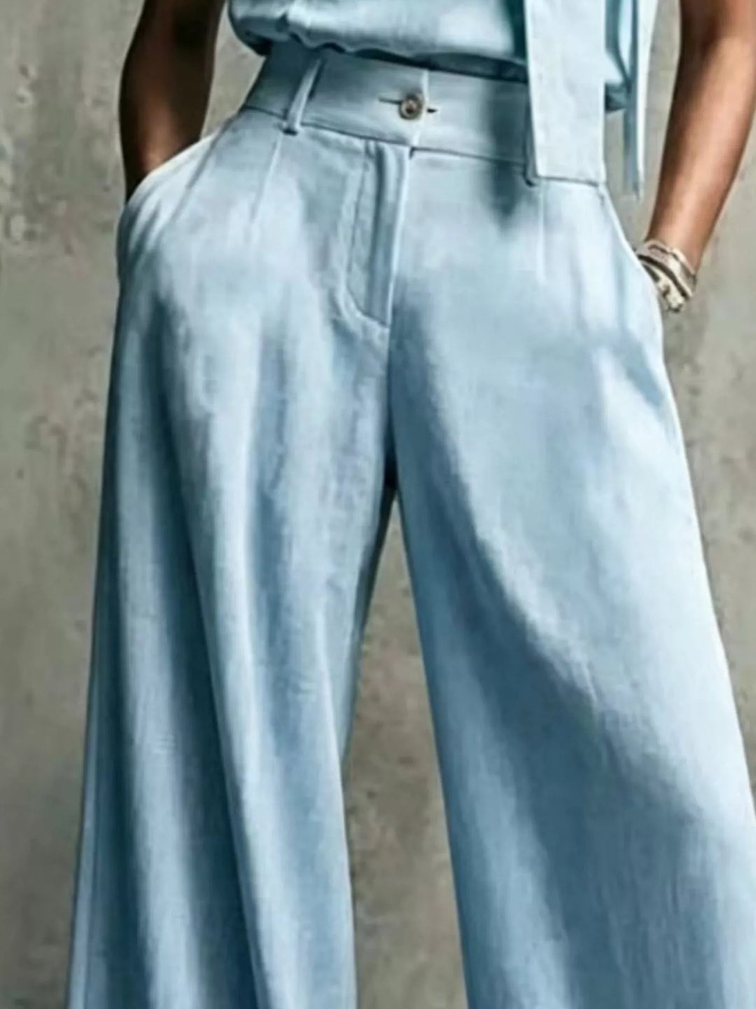 Light blue pleated trousers, close-up of the waist with button and zip