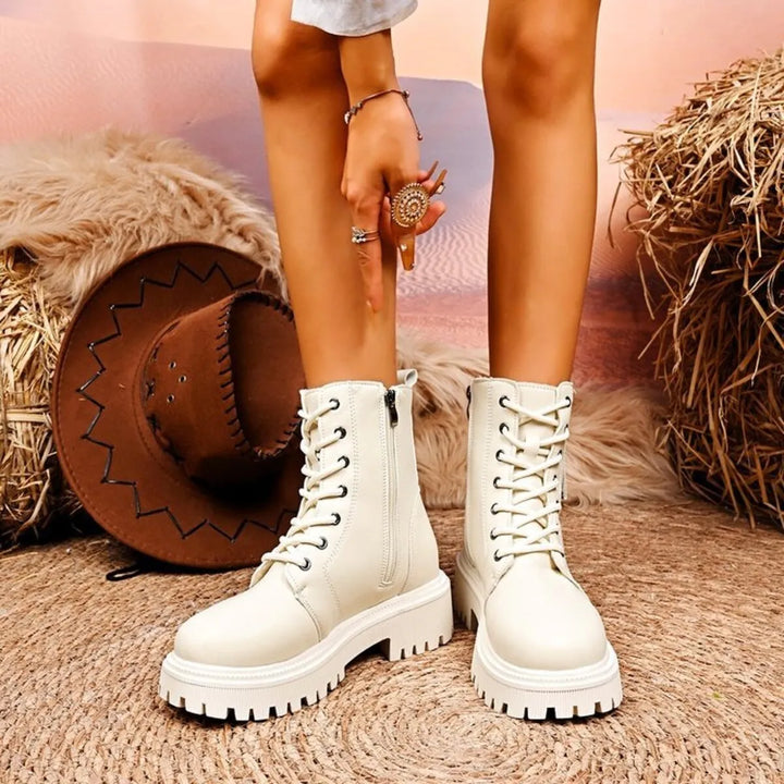Pair of ivory platform ankle boots with lace up front on a woven rug