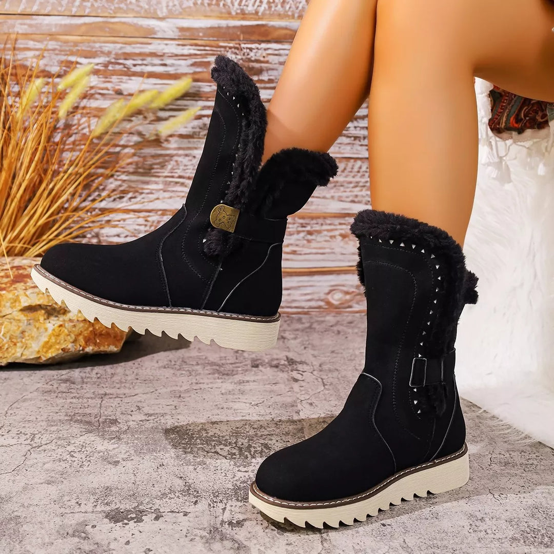 Black mid calf winter boot with faux fur trim and studded detail, seated pose