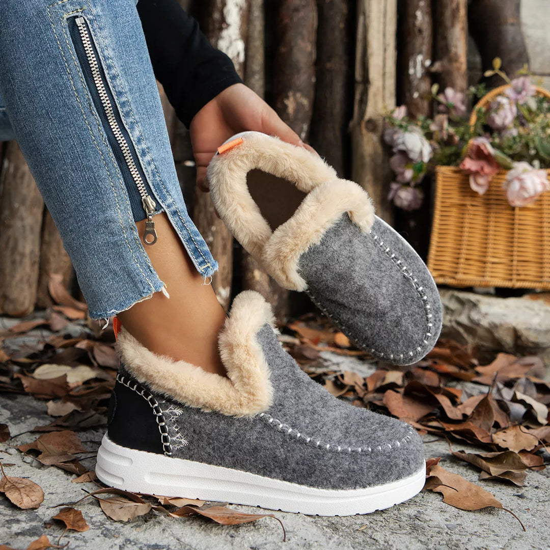 Gray plush collar ankle boots worn with zipper hem jeans, one boot lifted