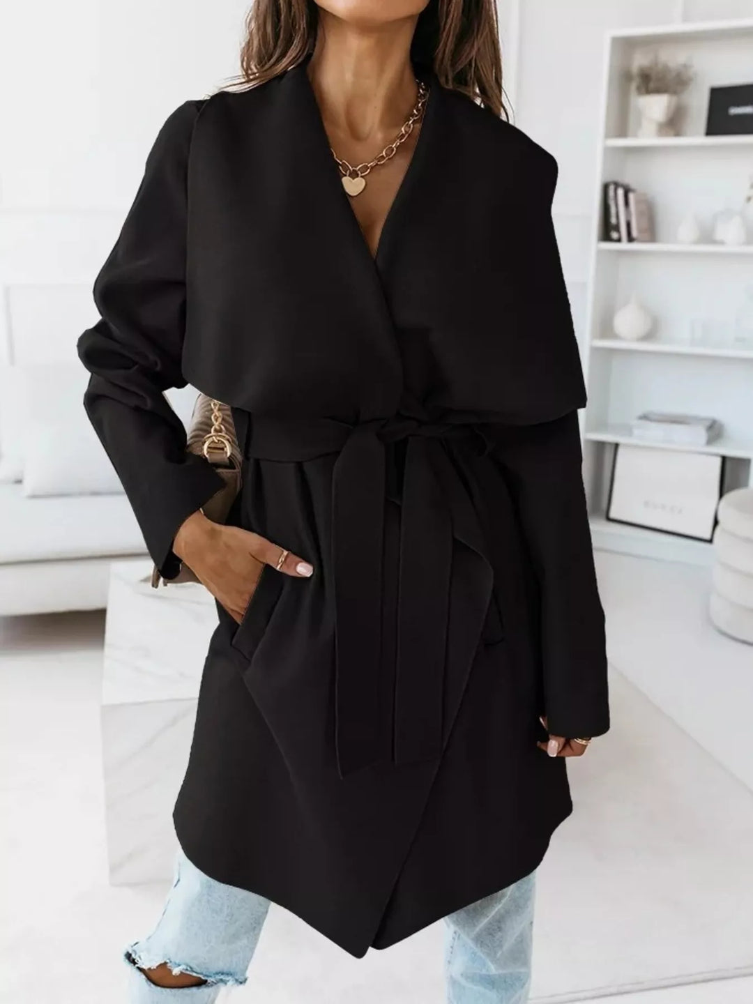 Black winter coat with belted waist and shawl lapel, hand in pocket