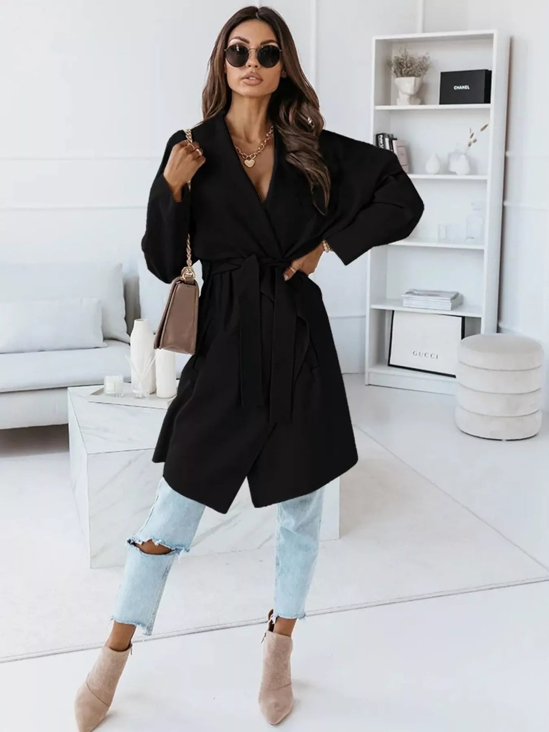 Full length black belted coat with light jeans and nude ankle boots