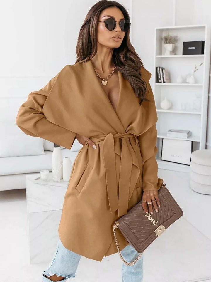 Camel belted winter coat with hand on hip, three quarter view