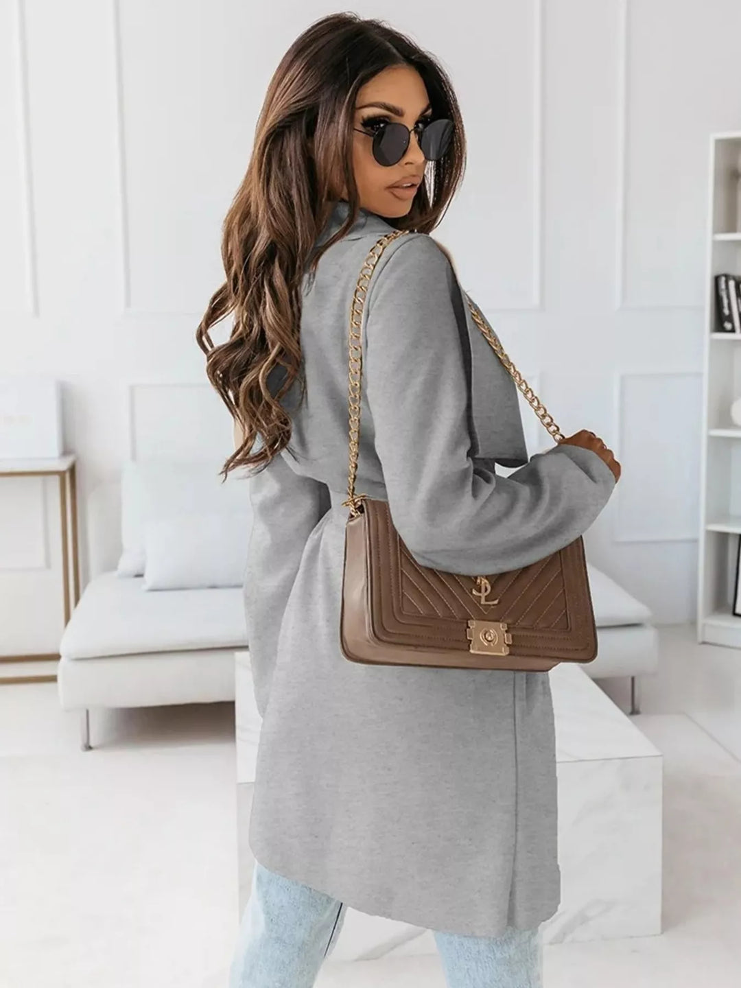 Gray belted coat seen from behind with a brown shoulder bag