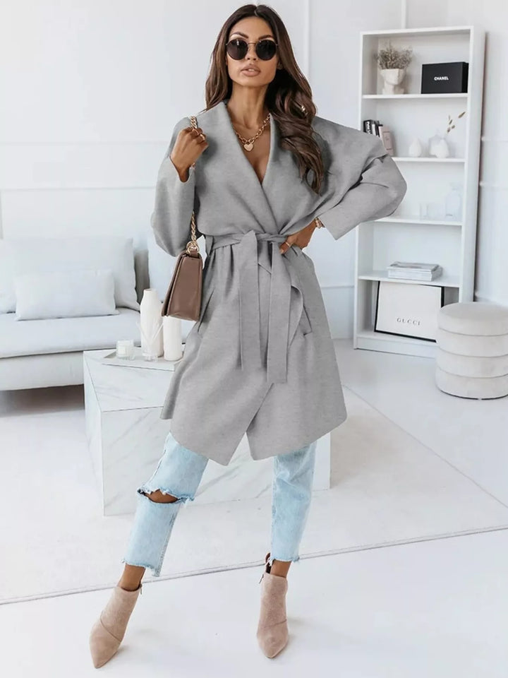 Full length gray belted coat with light jeans and heeled ankle boots