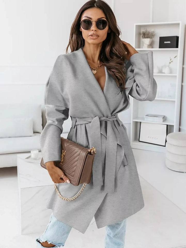 Gray belted winter coat styled with sunglasses and a quilted bag