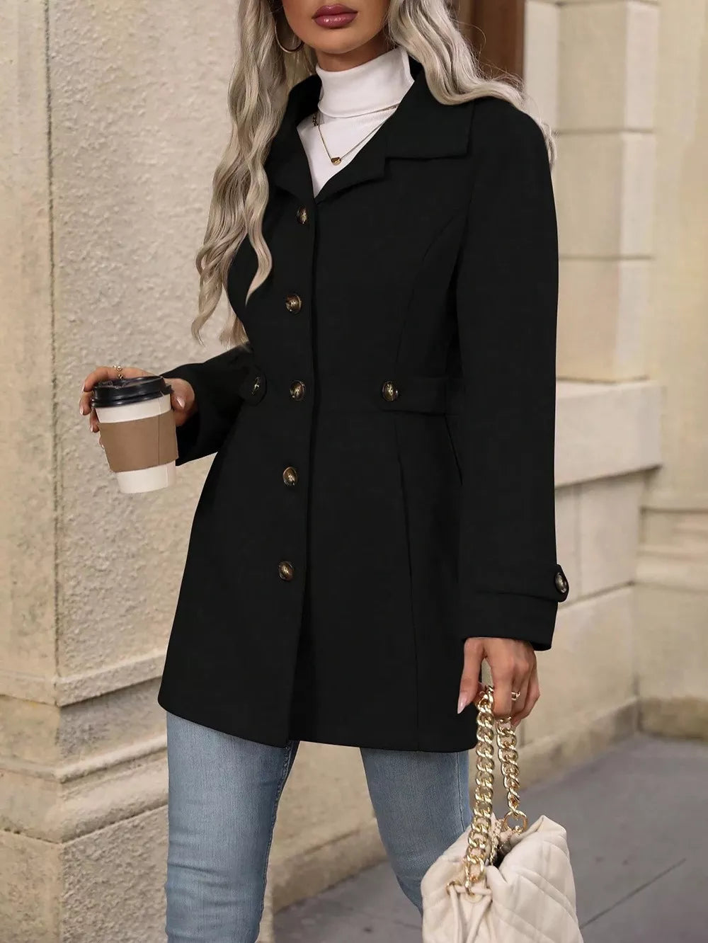 Black winter coat buttoned up with jeans and a quilted handbag