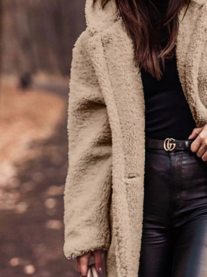 Close-up of the beige plush hooded coat with hand on the lapel