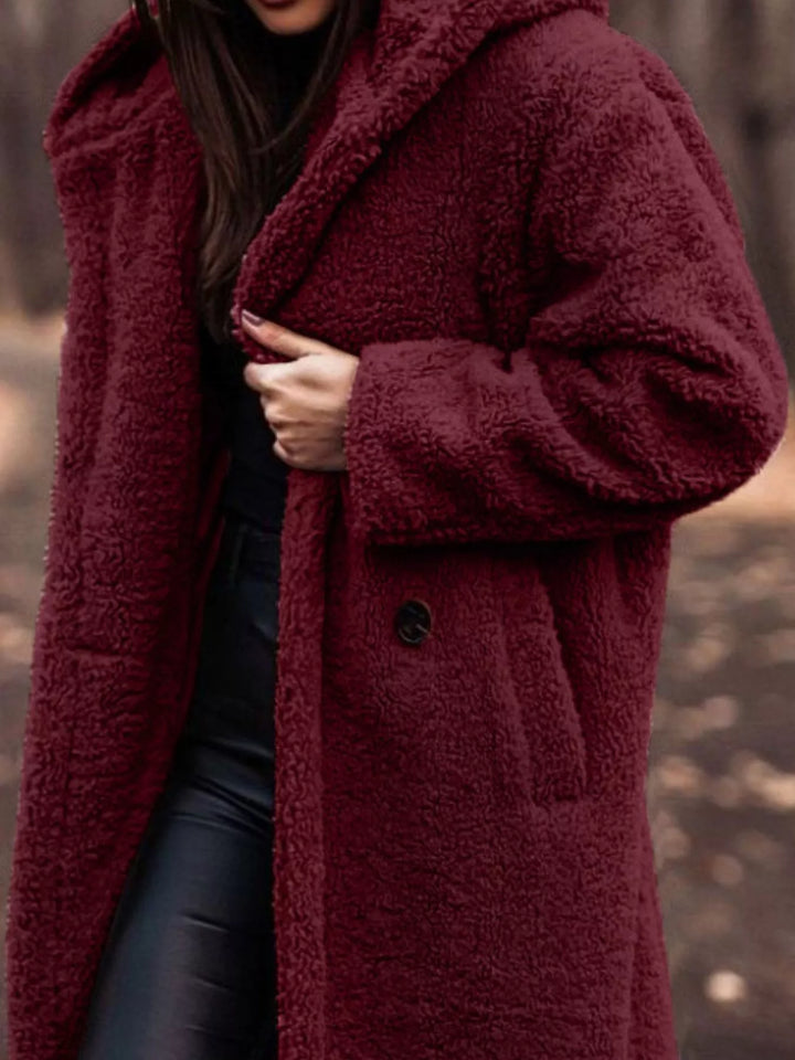 Close-up of the burgundy plush hooded coat with hand on the lapel