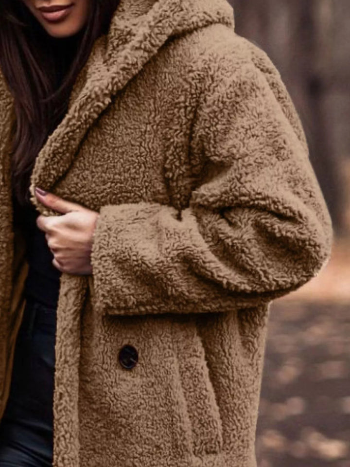 Close-up of the camel plush hooded coat with hand on the lapel