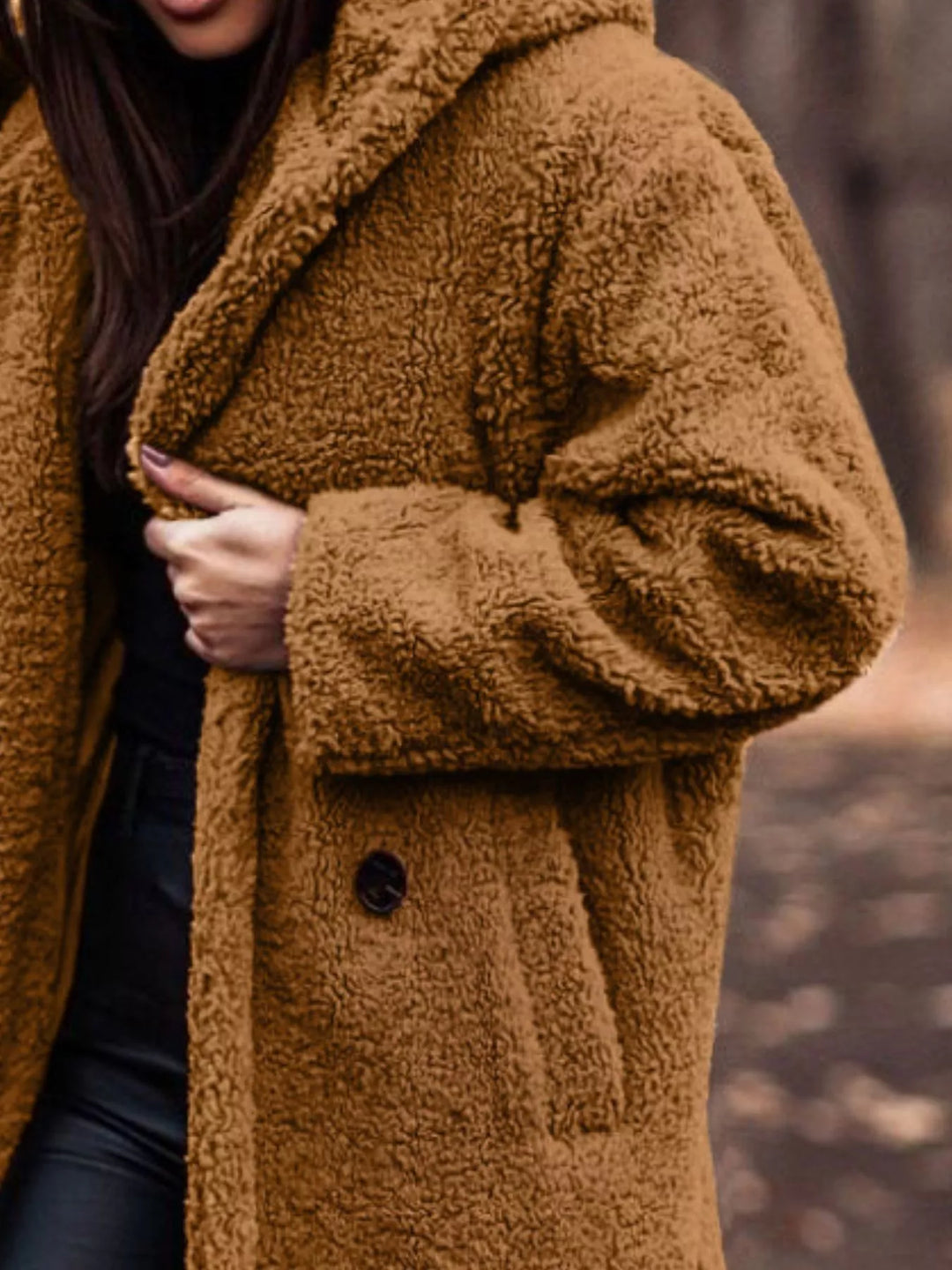 Close-up of the cognac plush hooded coat with hand on the lapel