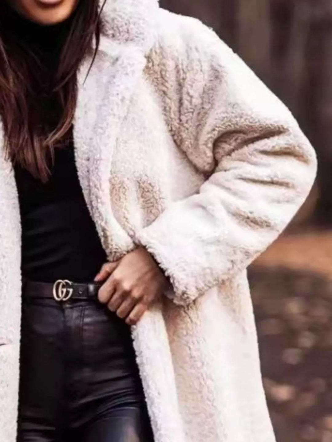 Close-up of the cream plush hooded coat with hand on the lapel