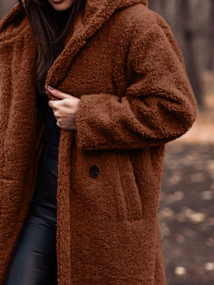 Close-up of the rust plush hooded coat with hand on the lapel